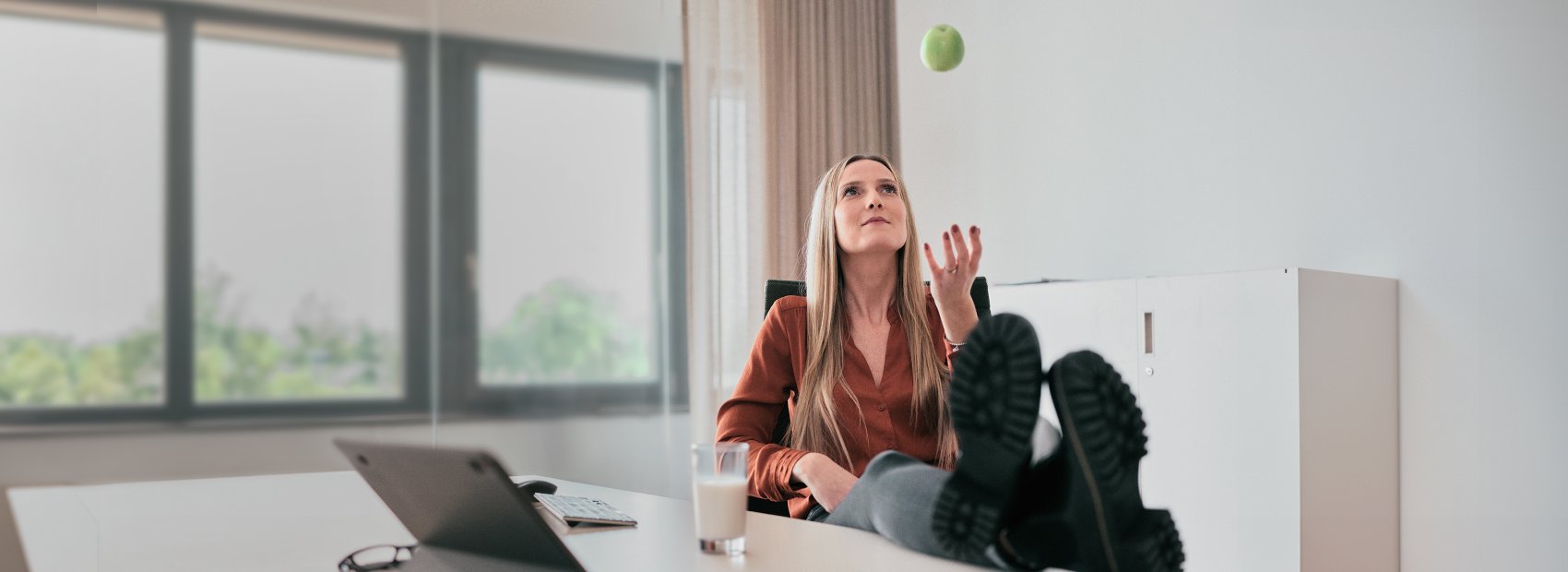 Frau wirft entspannt einen Apfel in die Luft, symbolisiert Extras zum Obstkorb
