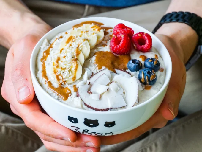 Eine Person hält eine Schüssel Porridge mit Beeren und Nüssen von 3Bears in der Hand