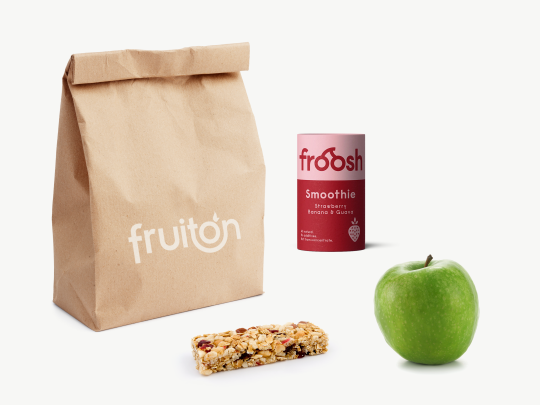 Papiertüte mit dem fruiton Logo, daneben ein Apfel, ein Smoothie und ein Müsliriegel.