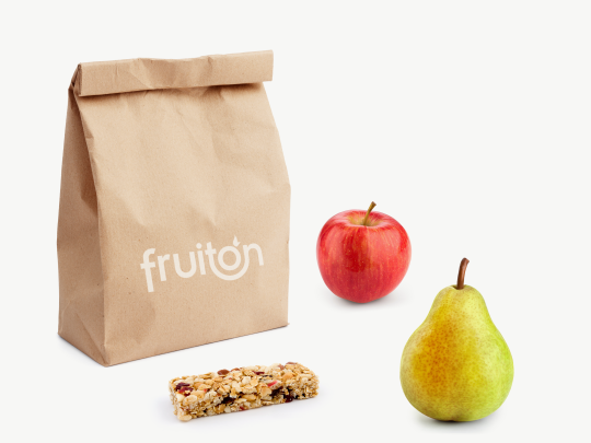 Papiertüte mit dem fruiton Logo, daneben ein Apfel, eine Birne und ein Müsliriegel.