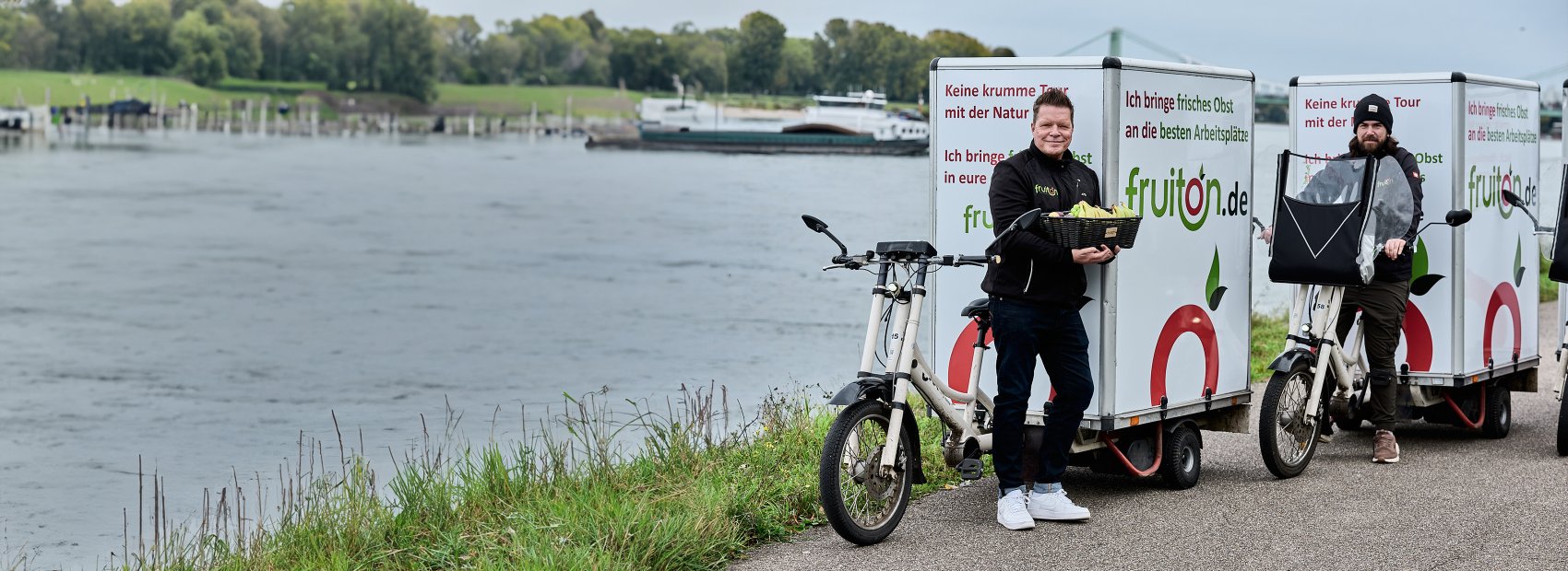 Zwei Personen auf Lasten-Fahrrädern, die das Konzept der nachhaltigen Lieferung und frische Produkte repräsentieren.