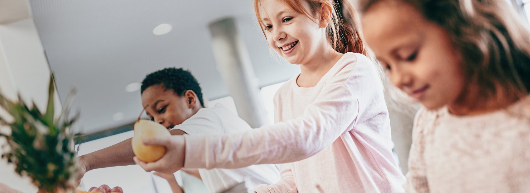 Kinder die in der Küche Obst zubereiten, ein Symbolbild für gesunde Ernährung in Schulen und Kitas.